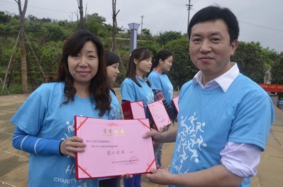 重慶江北希爾頓逸林酒店人力資源總監(jiān)曹麗女士（左一）從重慶市精神衛(wèi)生院院長(zhǎng)朱學(xué)文先生（右一）手中接過(guò)“第六屆重慶慧靈慈善慢跑愛(ài)心企業(yè)”榮譽(yù)證書(shū)